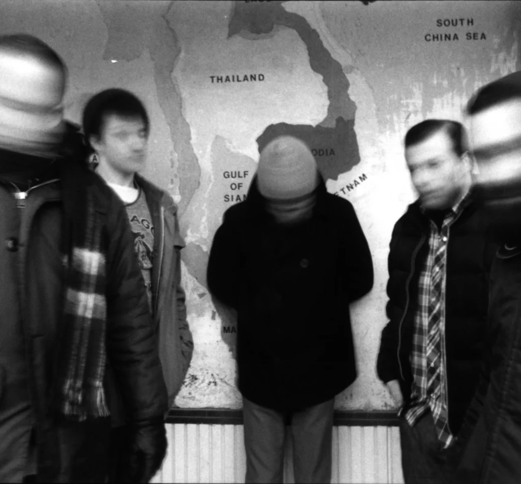 Five blurred figures stand in front of a map of Southeast Asia, with Thailand prominently displayed.