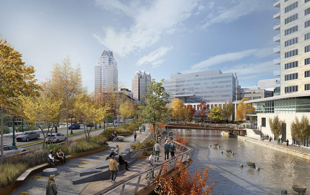 Urban park scene with people walking, sitting, and enjoying the waterfront, surrounded by autumn trees and buildings.