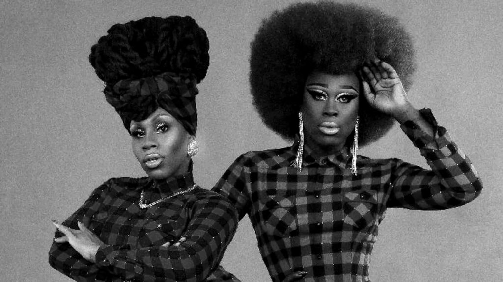 Two individuals pose confidently, wearing plaid shirts and bold hairstyles, showcasing their unique styles.