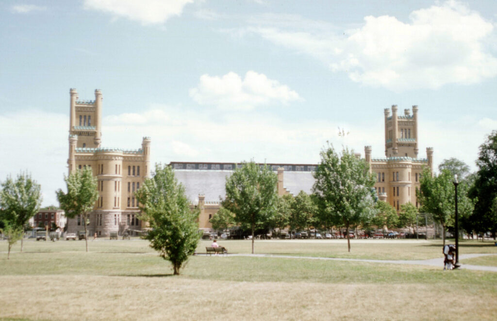 Historic Cranston Street Armory features twin towers, surrounded by trees and a grassy park area.