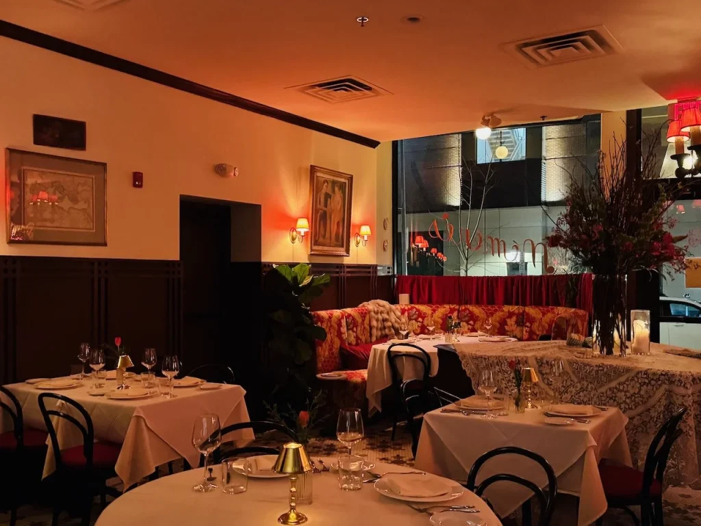 Elegant restaurant interior with tables set for dining, decorative plants, and warm lighting.