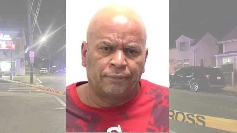 A man with a shaved head and red shirt looks directly at the camera. Background shows a police scene with caution tape.