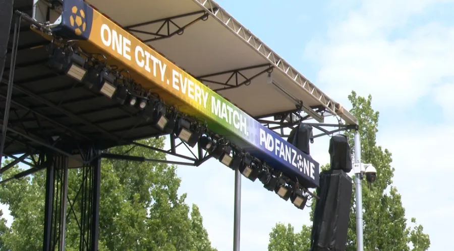 A stage banner reads "ONE CITY. EVERY MATCH. PVD FANZONE" with lights and trees in the background.
