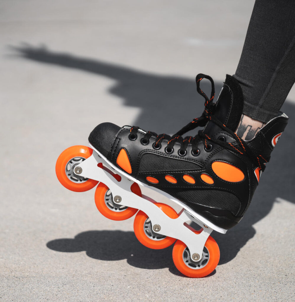 A close-up of a black roller skate with orange accents, resting on a smooth surface.