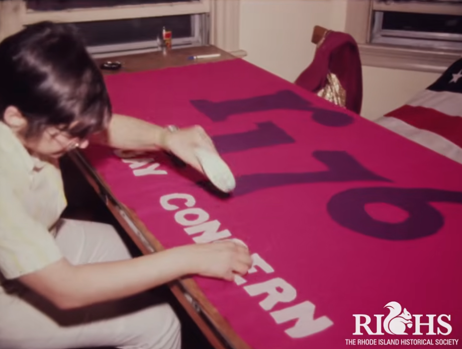 A person smooths a large pink banner with the number "176" and text on a table.