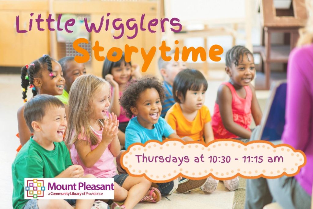 Children sit on the floor, smiling and engaged during a storytime session at the library.