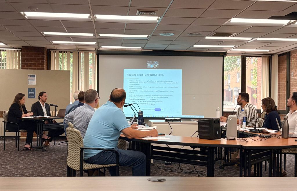 A group discusses the Housing Trust Fund, with a presentation displayed on a screen.