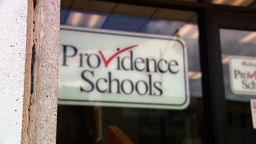 Close-up of a sign for Providence Schools on a building entrance.