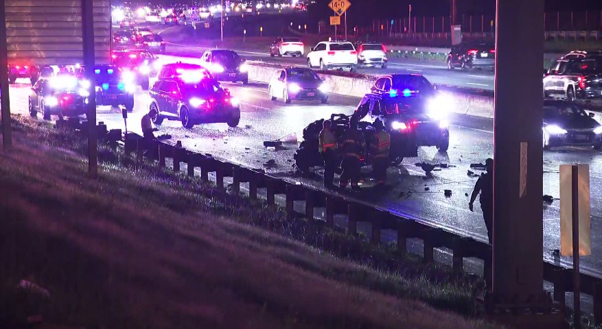 Emergency responders attend to a crash on I-95, with damaged vehicles and police lights flashing.