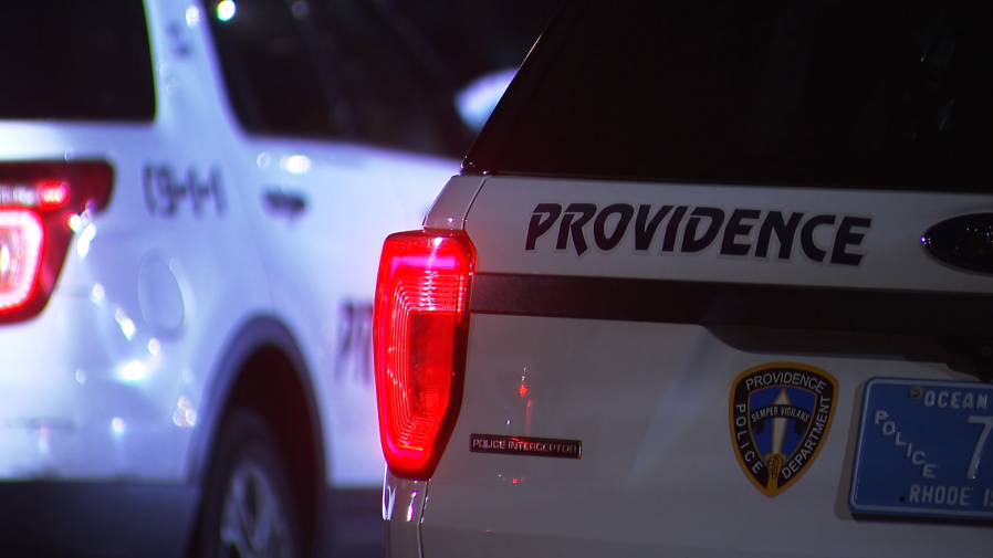 Two Providence police vehicles are parked, with one displaying the department's logo and lights.