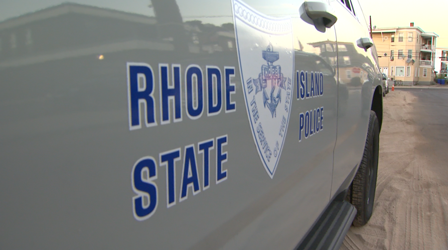 Rhode Island State Police vehicle parked on a street, displaying the department's logo and name.