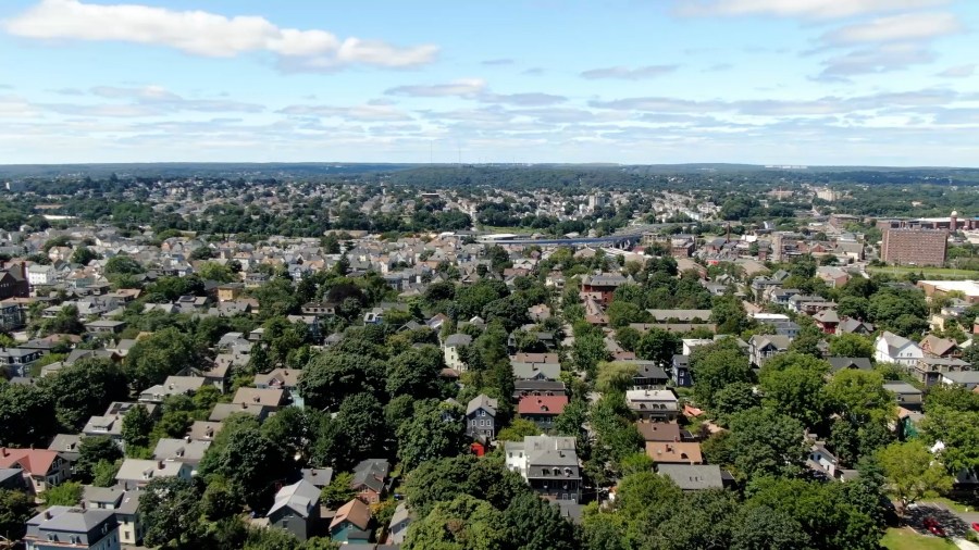 Aerial view of a densely populated neighborhood with houses and trees under a partly cloudy sky.
