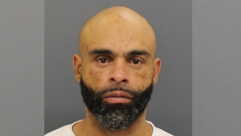A man with a bald head and beard stares directly at the camera, showing a serious expression.