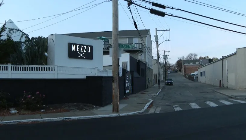 Exterior view of Mezzo Lounge with street signs and a quiet road. Power lines overhead.