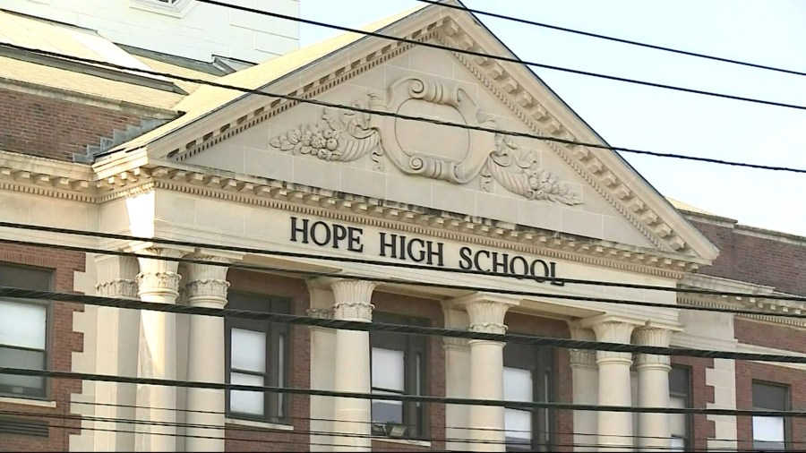 Facade of Hope High School features classical architecture and decorative elements. Power lines are visible in the foreground.