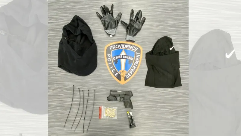 Black gloves, hooded garments, a firearm, ammunition, and a police badge arranged on a surface.