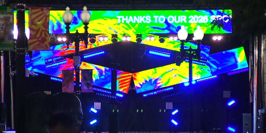 Colorful stage setup with vibrant lights and a banner thanking the 2026 SPC. Street lamps are visible.