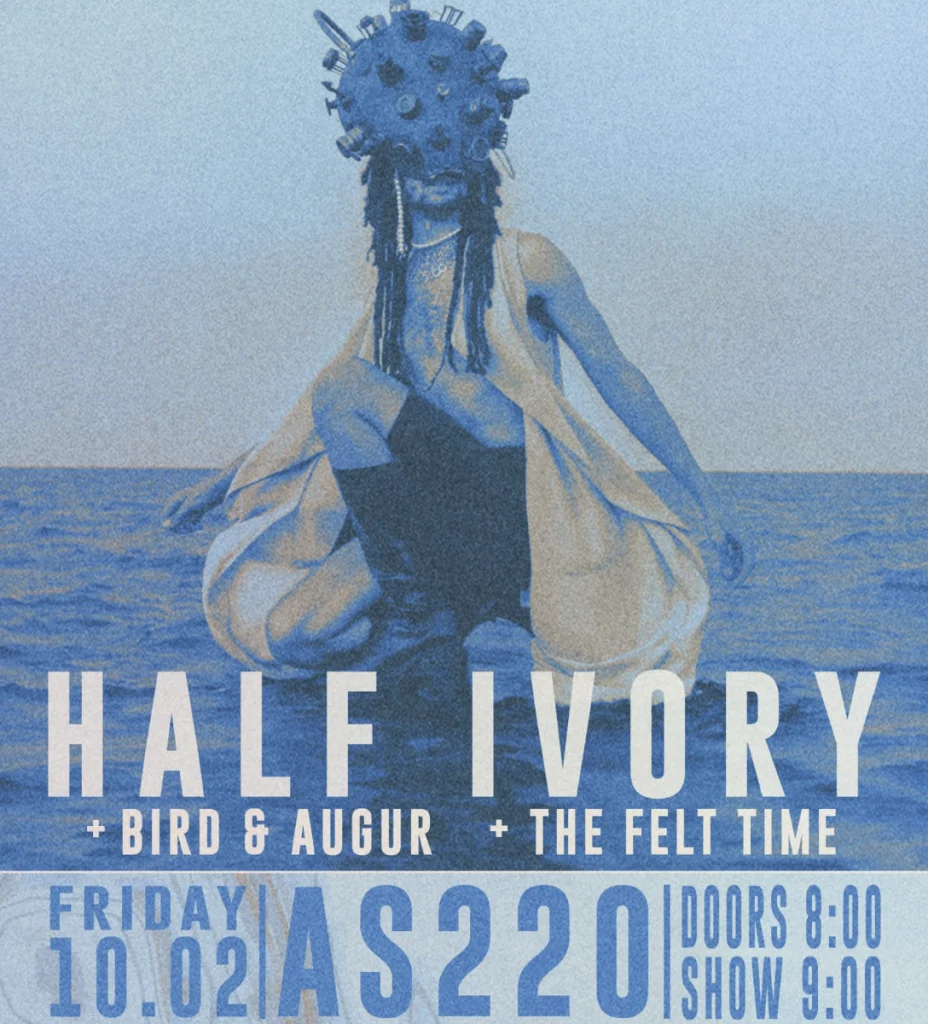 A person in a unique headpiece poses by the water, promoting the event "Half Ivory" with details below.