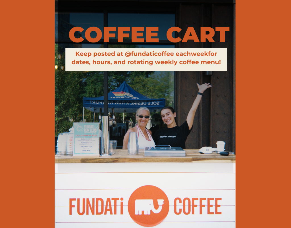 Two women stand behind a coffee cart, smiling and gesturing. A menu displays cold brew options.