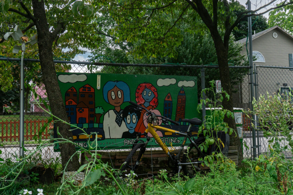 Colorful mural depicting two characters with blue and red hair, surrounded by buildings and a bicycle in front.
