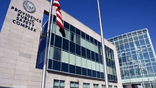 Modern building of the Providence Public Safety Complex with glass and stone facade, featuring an American flag.