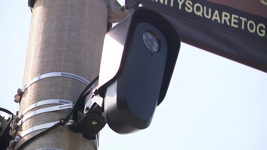 A black camera mounted on a utility pole, capturing images in a public area.