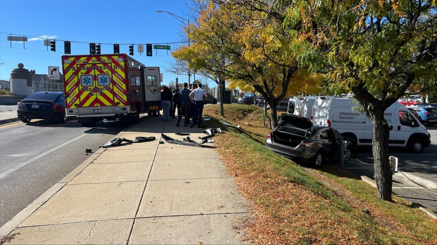 Emergency responders gather near a damaged ambulance and two vehicles after a collision on a busy street.