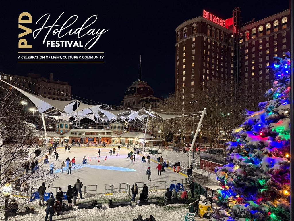 People skate on an outdoor rink surrounded by snow and festive lights, with a decorated tree nearby.